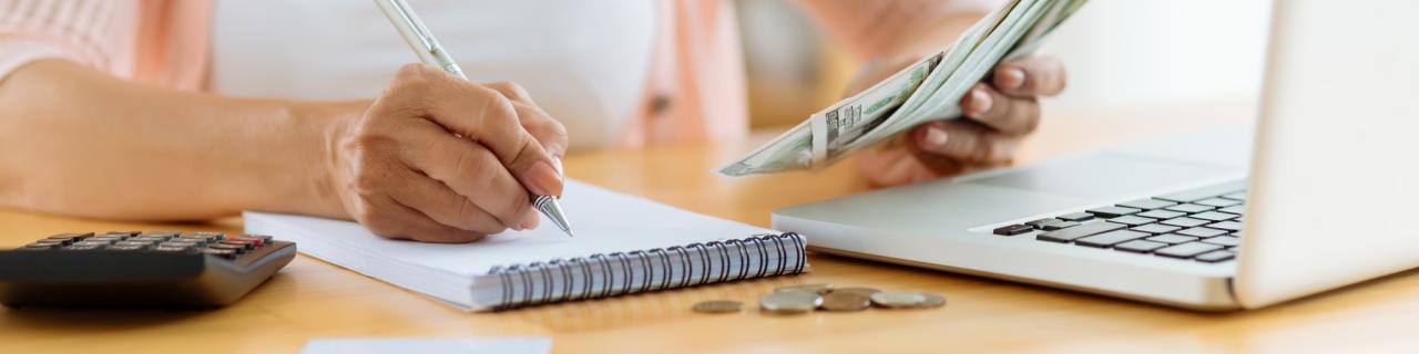 woman writing on paper with money in hand