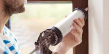 man holding air sealing gun near window